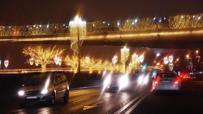 Автомобили едут по набережной вечером Автомобили едут по набережной вечером