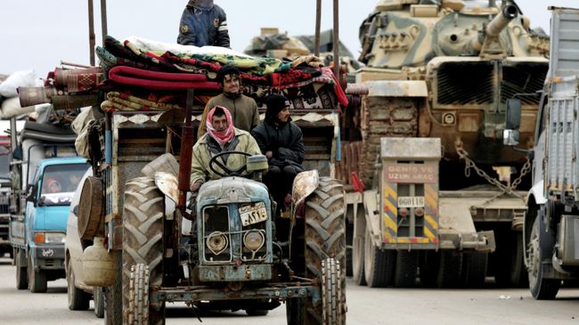 Покинувшие свои дома сирийцы и колонна турецкой военной техники в Хазано, недалеко от Идлиба Покинувшие свои дома сирийцы и колонна турецкой военной техники в Хазано, недалеко от Идлиба