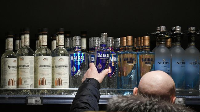 Мужчина выбирает алкогольную продукцию в супермаркете 