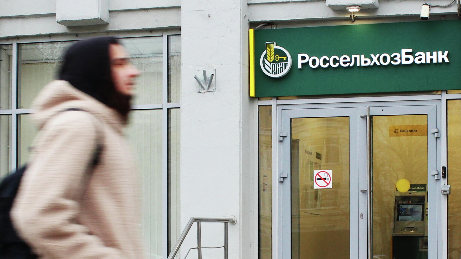 Прохожий около входа в офис банка Россельхозбанк на одной из улиц в Москве - РИА Новости, 1920, 16.02.2026