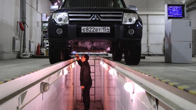 Технический эксперт проводит осмотр автомобиля на пункте техосмотра в Новосибирске