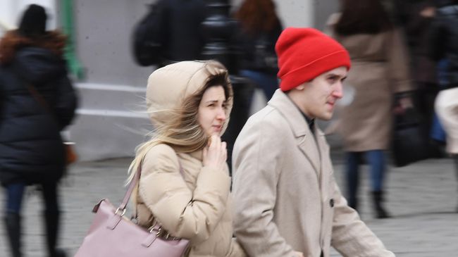 Люди идут по улице под порывами ветра в Москве Люди идут по улице под порывами ветра в Москве