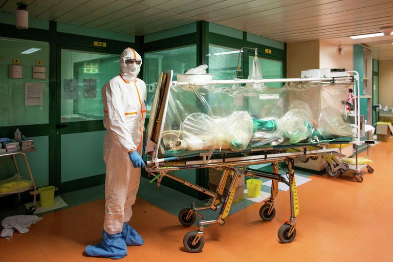 Медицинские работники в защитных костюмах транспортируют больного коронавирусом в больницу Коламбус Ковид, Италия Медицинские работники в защитных костюмах транспортируют больного коронавирусом в больницу Коламбус Ковид, Италия