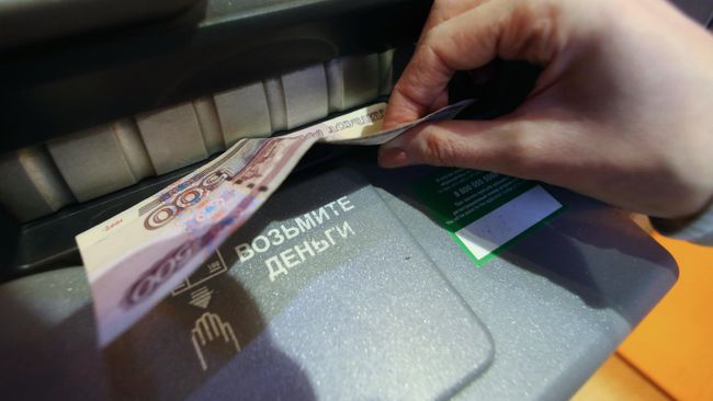 Женщина получает наличные деньги в банкомате Женщина получает наличные деньги в банкомате
