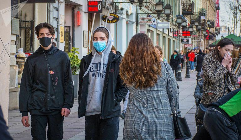 Прохожие в медицинских масках на улице Тбилиси