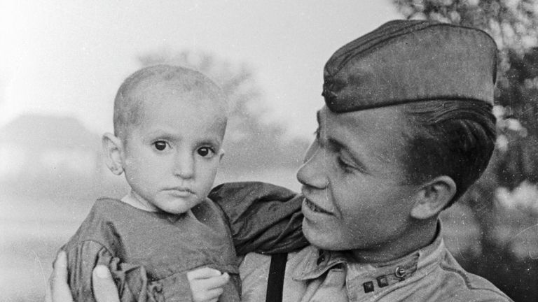 Советский офицер держит на руках спасённую им девочку из деревни Эльхотово