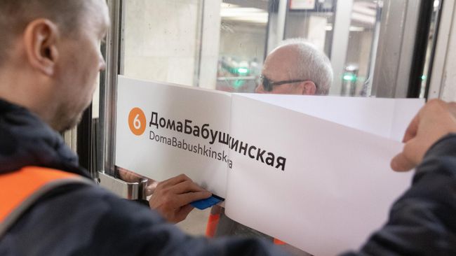 Сотрудник метрополитена приклеивает на двери стикер ДомаБабушкинская Сотрудник метрополитена приклеивает на двери стикер ДомаБабушкинская