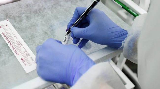 Сотрудник лаборатории подписывает тест на COVID-19 Сотрудник лаборатории подписывает тест на COVID-19