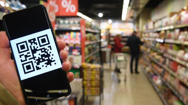 Человек держит смартфон с изображением QR-кода Человек держит смартфон с изображением QR-кода