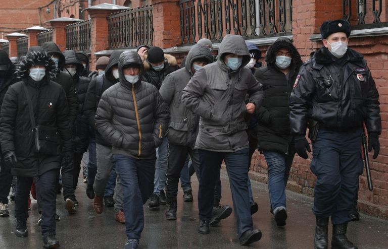 Сотрудник полиции выстраивает в очередь мигрантов у здания УФМС в Санкт-Петербурге
