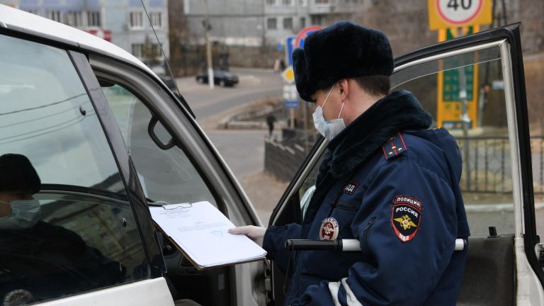 Сотрудник ГИБДД проверяет справку для работающих в Чите Сотрудник ГИБДД проверяет справку для работающих в Чите