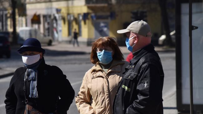 Прохожие в защитных масках на улице во Львове Прохожие в защитных масках на улице во Львове