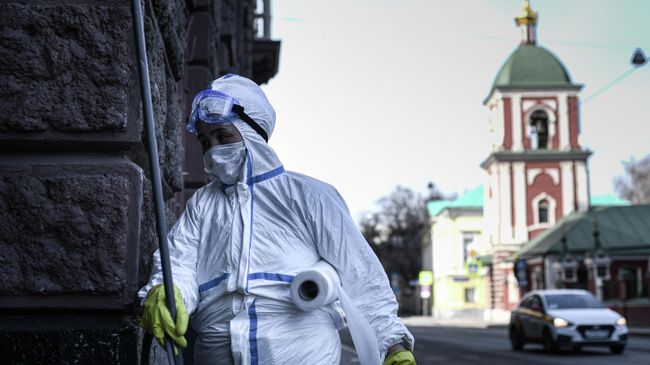 Сотрудник коммунальной службы в защитном костюме во время работы в центре Москвы Сотрудник коммунальной службы в защитном костюме во время работы в центре Москвы