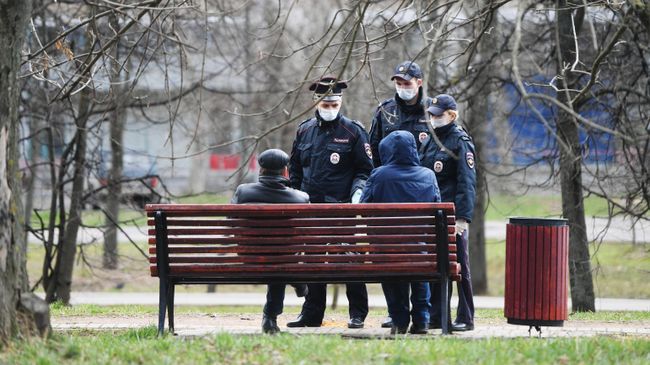 Сотрудники полиции разговаривают с людьми, сидящими на скамейке в сквере Сотрудники полиции разговаривают с людьми, сидящими на скамейке в сквере