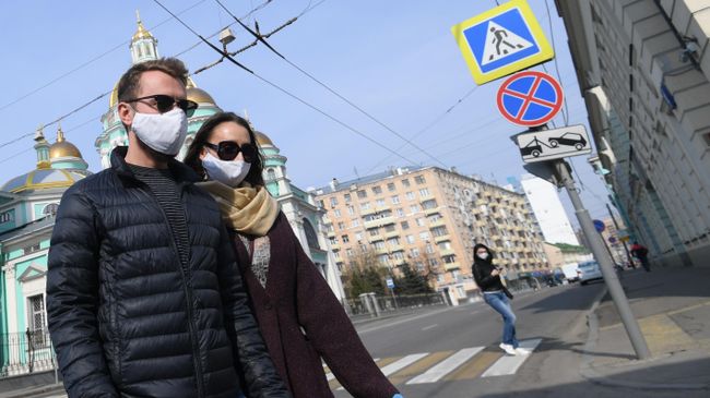 Молодые люди в защитных масках и перчатках на одной из улиц Москвы Молодые люди в защитных масках и перчатках на одной из улиц Москвы