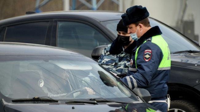 Сотрудники дорожно-патрульной службы ГИБДД проверяют документы у водителя на блокпосту при въезде в Москву на пересечении с МКАД