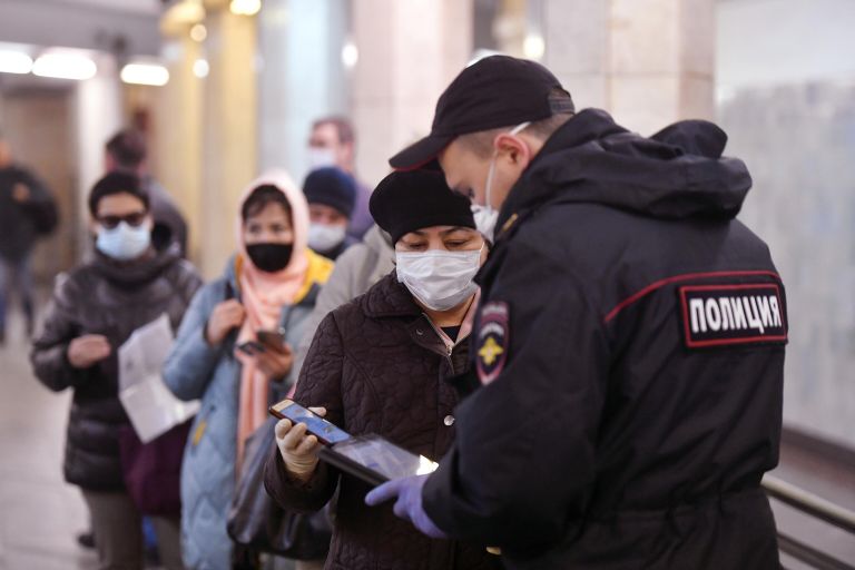 Пассажирка метро показывает код своего электронного пропуска на экране смартфона сотруднику полиции на станции метро Сокольники в Москве Пассажирка метро показывает код своего электронного пропуска на экране смартфона сотруднику полиции на станции метро Сокольники в Москве