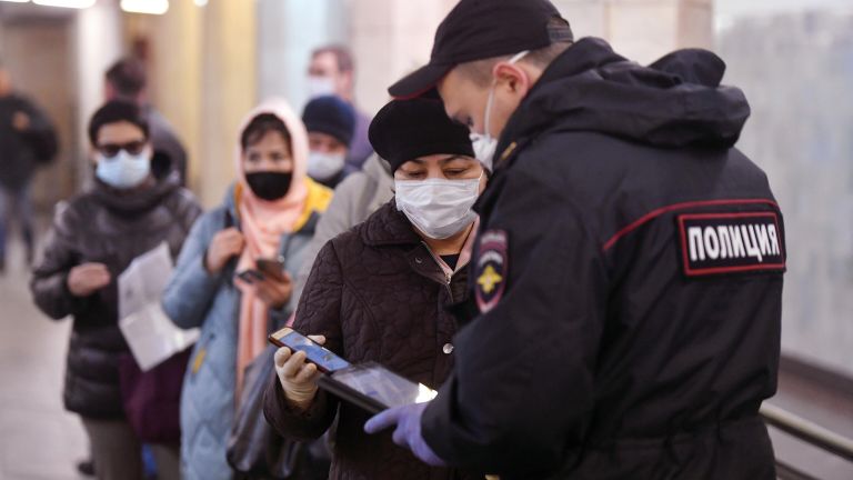 Пассажирка метро показывает код своего электронного пропуска на экране смартфона сотруднику полиции на станции метро Сокольники в Москве Пассажирка метро показывает код своего электронного пропуска на экране смартфона сотруднику полиции на станции метро Сокольники в Москве