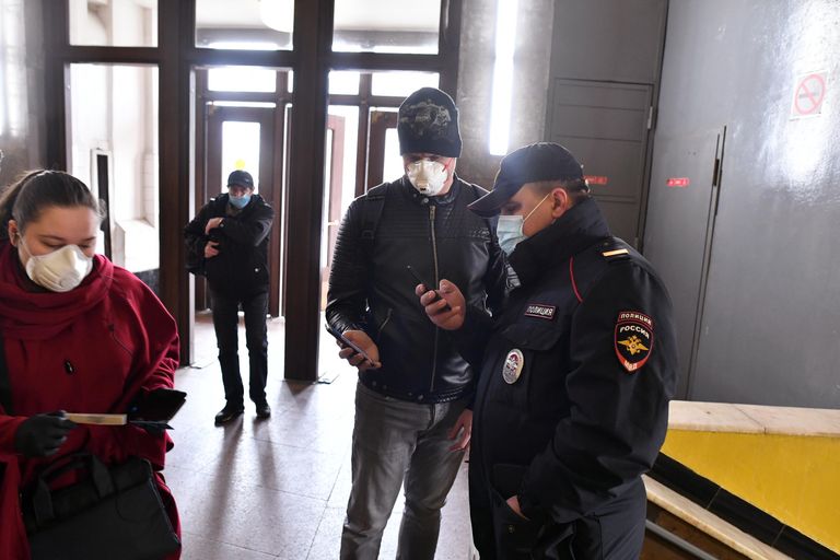 Пассажир метро показывает код своего электронного пропуска на экране смартфона сотруднику полиции на станции метро Сокольники в Москве Пассажир метро показывает код своего электронного пропуска на экране смартфона сотруднику полиции на станции метро Сокольники в Москве