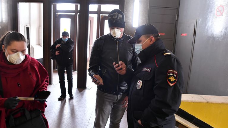 Пассажир метро показывает код своего электронного пропуска на экране смартфона сотруднику полиции на станции метро Сокольники в Москве Пассажир метро показывает код своего электронного пропуска на экране смартфона сотруднику полиции на станции метро Сокольники в Москве
