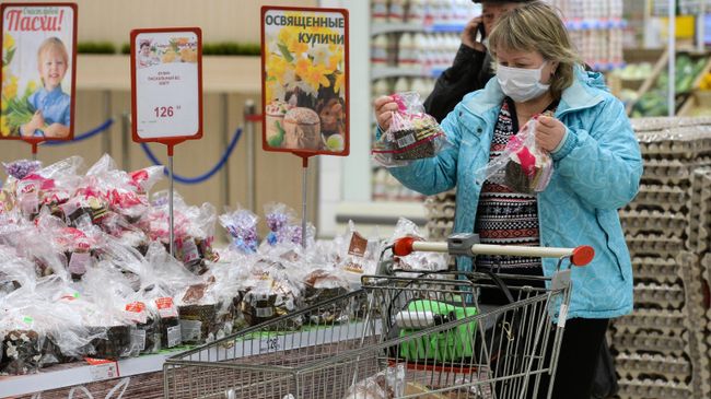 Женщина выбирает пасхальные куличи в суперрмаркете Женщина выбирает пасхальные куличи в суперрмаркете