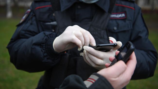Сотрудник полиции проверяет цифровой пропуск у прохожего в Москве Сотрудник полиции проверяет цифровой пропуск у прохожего в Москве
