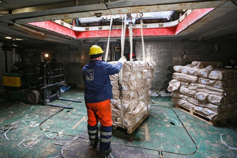 Моряки выгружают рыбу из транспортного судна (рефрижератора) Выборгский у причала Мурманского морского рыбного порта.