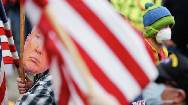 Мужчина в маске Дональда Трампа во время протеста против режима самоизоляции в Вашингтоне, США Мужчина в маске Дональда Трампа во время протеста против режима самоизоляции в Вашингтоне, США