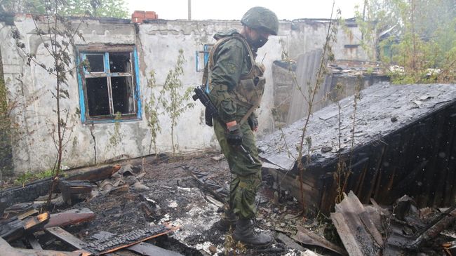 Военнослужащий НМ ДНР осматривает сгоревший после обстрела дом в поселке Шахты 6-7 в Горловке Военнослужащий НМ ДНР осматривает сгоревший после обстрела дом в поселке Шахты 6-7 в Горловке