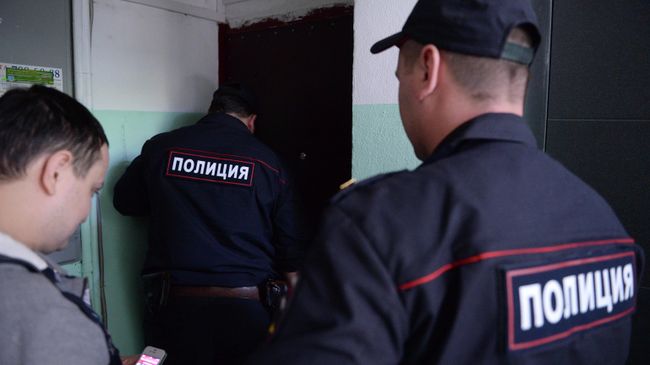 Сотрудники полиции стоят у двери квартиры в жилом доме