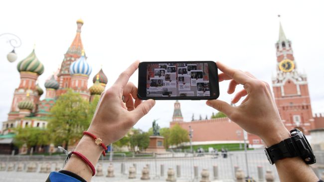 Молодой человек смотрит трансляцию акции Бессмертный полк на Красной площади в Москве Молодой человек смотрит трансляцию акции Бессмертный полк на Красной площади в Москве
