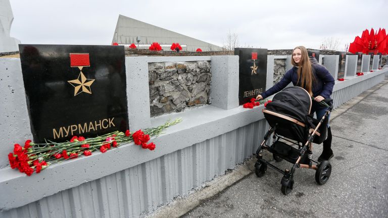 Девушка возлагает цветы к обелиску Города-герои в Мурманске Девушка возлагает цветы к обелиску Города-герои в Мурманске