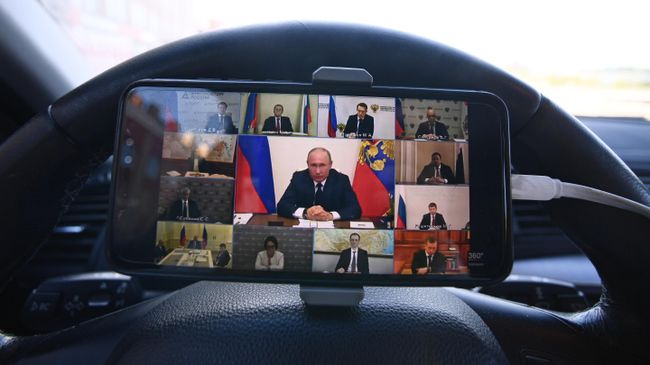 Мужчина смотрит трансляцию обращения президента России Владимира Путина в связи с ситуацией, связанной с распространением коронавируса в своем автомобиле в Москве Мужчина смотрит трансляцию обращения президента России Владимира Путина в связи с ситуацией, связанной с распространением коронавируса в своем автомобиле в Москве