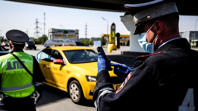 Сотрудники дорожно-патрульной службы ГИБДД во время проверки наличия пропуска у водителя на блокпосту в Москве Сотрудники дорожно-патрульной службы ГИБДД во время проверки наличия пропуска у водителя на блокпосту в Москве