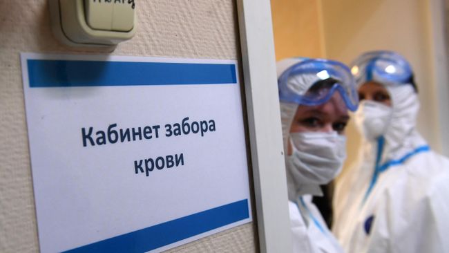 Медицинские работники в защитных костюмах у кабинета забора крови на наличие антител к COVID-19 Медицинские работники в защитных костюмах у кабинета забора крови на наличие антител к COVID-19