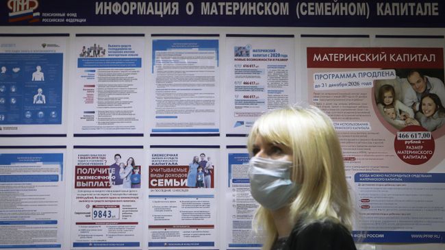 Посетительница возле информационного стенда о материнском капитале в отделении пенсионного фонда Посетительница возле информационного стенда о материнском капитале в отделении пенсионного фонда