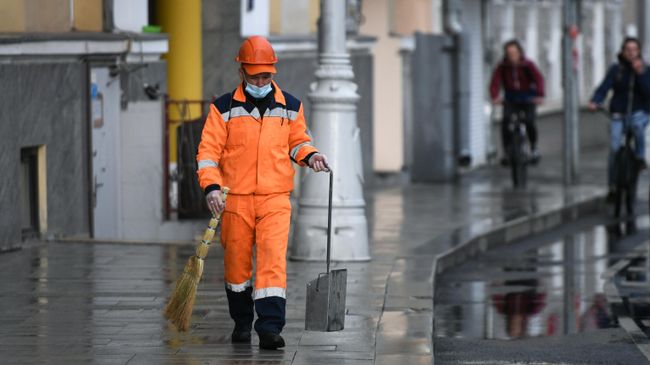 Сотрудник коммунальной службы убирает улицу в Москве Сотрудник коммунальной службы убирает улицу в Москве