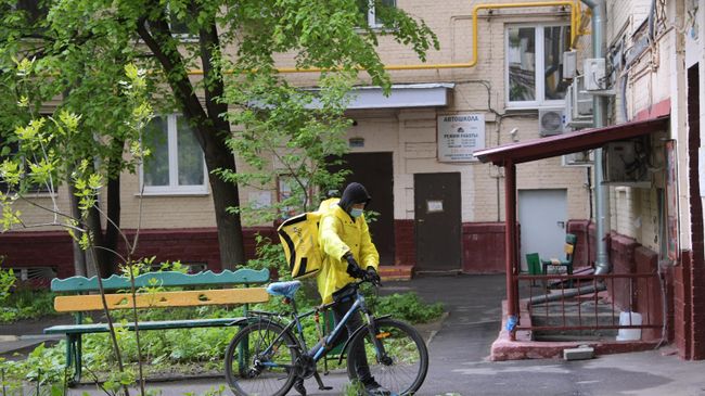 Курьер службы доставки Яндекс Еда у подъезда жилого дома на Ленинском проспекте в Москве Курьер службы доставки Яндекс Еда у подъезда жилого дома на Ленинском проспекте в Москве