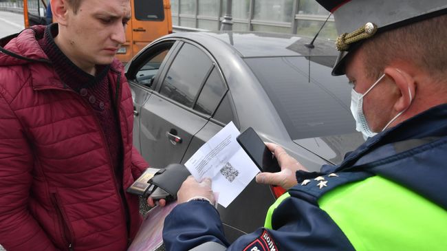 Инспектор ДПС проверяет цифровой пропуск у водителя Инспектор ДПС проверяет цифровой пропуск у водителя