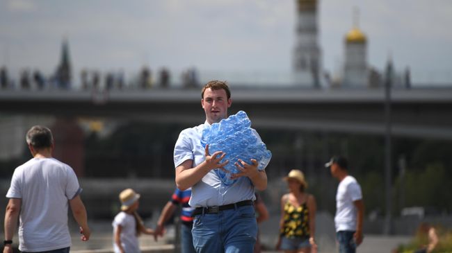 Прохожий с упаковкой питьевой воды в окрестностях парка Зарядье в Москве Прохожий с упаковкой питьевой воды в окрестностях парка Зарядье в Москве