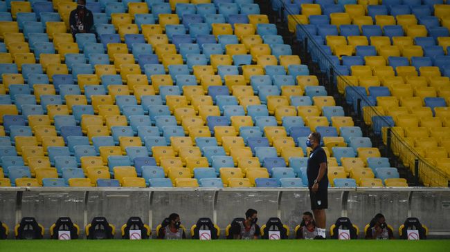 Flamengo team players remain sitting on the bench respecting security distances during a Carioca Championship 2020 football match against Bangu at the Maracana stadium, in Rio de Janeiro, Brazil, on June 18, 2020, which is played behind closed doors as the city gradually eases its social distancing measures aimed at curbing the spread of the COVID-19 coronavirus. (Photo by MAURO PIMENTEL / AFP)