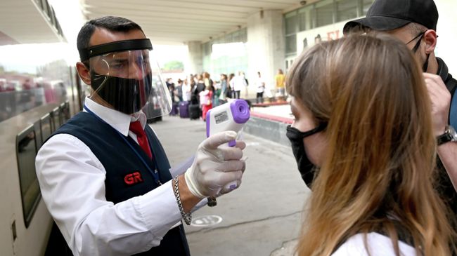 Проводник проверяет температуру у пассажиров на железнодорожном вокзале в Тбилиси Проводник проверяет температуру у пассажиров на железнодорожном вокзале в Тбилиси