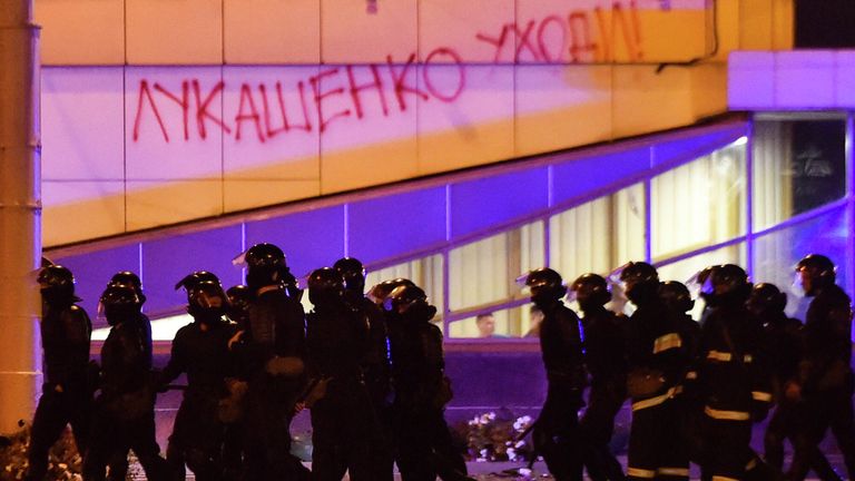 Сотрудники правоохранительных органов проходят мимо здания с надписью Лукашенко уходи! во время массовой акции протеста после президентских выборов в Минске, Беларусь Сотрудники правоохранительных органов проходят мимо здания с надписью Лукашенко уходи! во время массовой акции протеста после президентских выборов в Минске, Беларусь