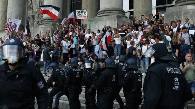 Полицейские перед зданием Рейхстага во время митинга против правительственных ограничений после вспышки COVID-19 в Берлине, Германия Полицейские перед зданием Рейхстага во время митинга против правительственных ограничений после вспышки COVID-19 в Берлине, Германия