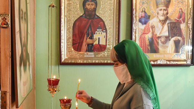 Верующая в медицинской маске во время Божественной литургии в день Лазаревой субботы в православном Храме Святаго Князя Даниила Московского в селе Бартат Красноярского кра
