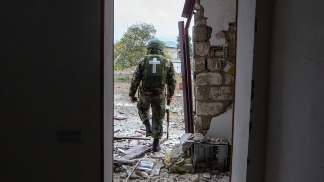 Военнослужащий возле дома, поврежденного в результате обстрела Степанакерта