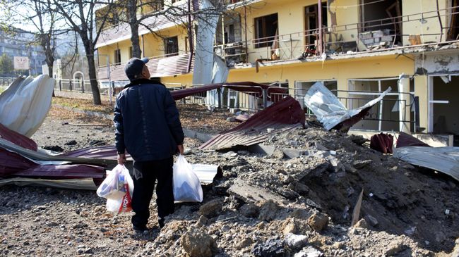 Мужчина возле дома, пострадавшего в результате обстрела города Шуша