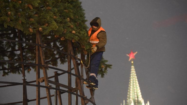 Рабочий устанавливает новогоднюю елку на Красной площади в Москве Рабочий устанавливает новогоднюю елку на Красной площади в Москве