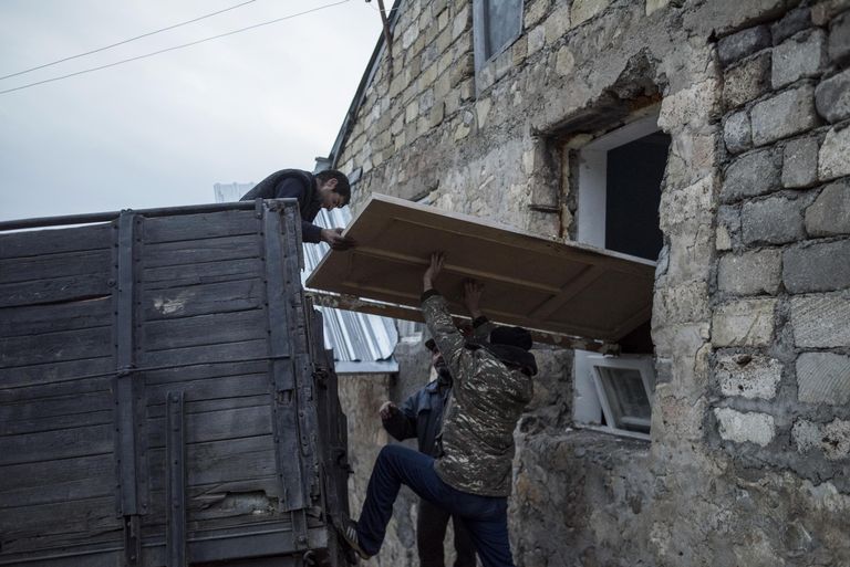 Мужчины загружают дверь в кузов грузового автомобиля в поселке Карегах в Нагорном Карабахе Мужчины загружают дверь в кузов грузового автомобиля в поселке Карегах в Нагорном Карабахе