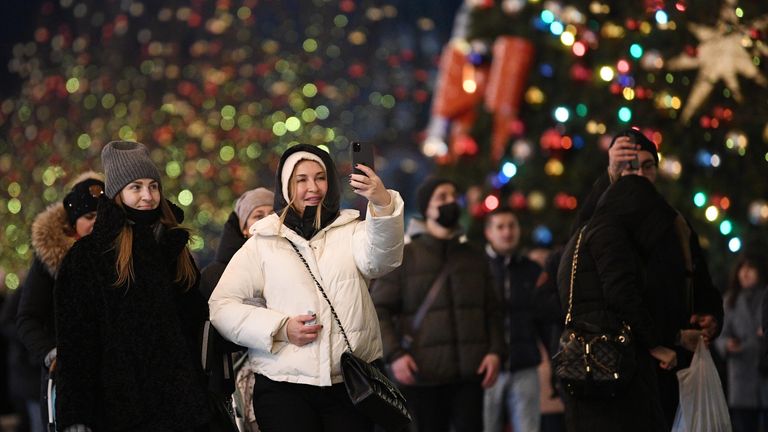 Прохожие на украшенной к Новому Году Красной площади в Москве Прохожие на украшенной к Новому Году Красной площади в Москве